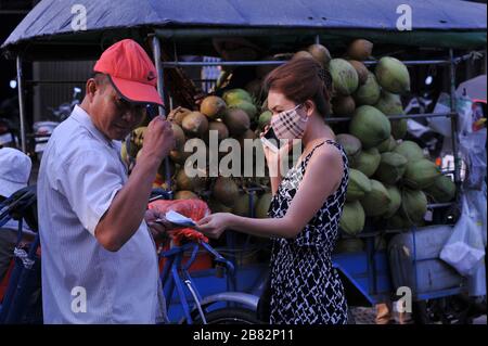 Livraison de noix de coco, femme cambodgienne avec masque utilisant un smartphone au marché de Kandal pendant la pandémie du coronavirus. Phnom Penh, Cambodge. © Kraig Lieb Banque D'Images
