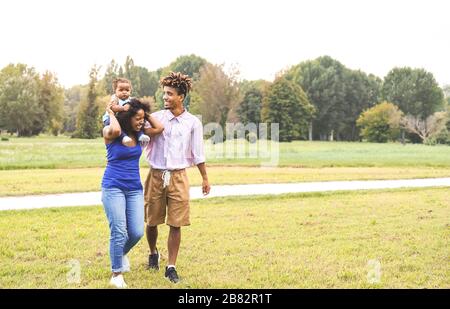 Bonne famille africaine s'amuser dans le parc public - mère et père avec leur fille profiter ensemble pendant le week-end ensoleillé jour plein air Banque D'Images