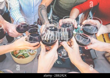 Bonne dégustation familiale avec des verres à vin rouge au dîner en plein air - les gens s'amusent à se faire plaisir et à boire tout en dînant ensemble Banque D'Images