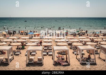 Plage bondée avec parasols blancs Banque D'Images