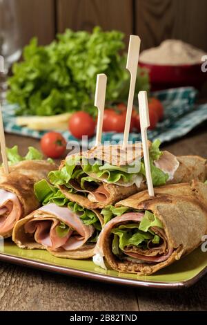 Crêpes salées de farine de mil remplies de jambon, de fromage et de salade de laitue. Banque D'Images