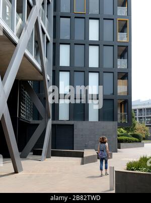 Femme marchant entre de nouveaux blocs d'appartements au Trenerry Crescent, Melbourne. Australie Banque D'Images