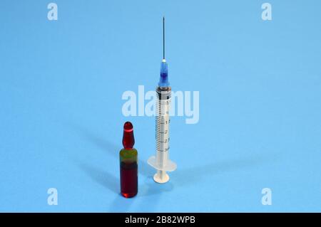 Ampoule avec vaccin et seringue sur fond bleu, concept de vaccination contre la grippe, médicament pour tous les virus Banque D'Images