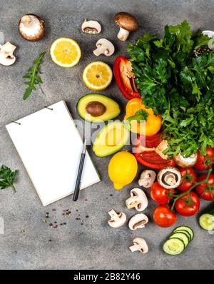 Différents légumes et ingrédients pour la cuisine des plats végétaliens. Un livre pour écrire des recettes se trouve sur une table. Espace de copie pour le texte Banque D'Images