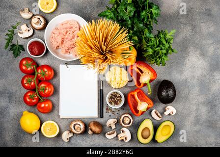 Ingrédients pour la fabrication de pâtes. Un livre pour écrire des recettes se trouve sur une table entourée de nourriture. Espace de copie pour le texte. Banque D'Images