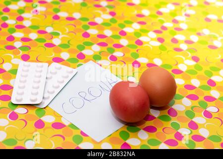 Pilules blanches et œufs sur un fond jaune personnalisé. Papier avec inscription CORONA. Pâques durant l'éclosion du virus corona, covid-19 dans le monde crysis in e Banque D'Images