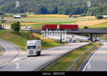 Paysage autoroutier avec camion blanc sur route et camion rouge tirant la remorque sur le pont. Salo, Finlande. 19 juillet 2019. Banque D'Images