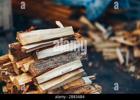 Un tas de bois de chauffage empilé, préparé pour chauffer la maison. Collecte de bois de feu pour l'hiver ou le feu de joie. L'homme tient le bois de feu dans les mains Banque D'Images