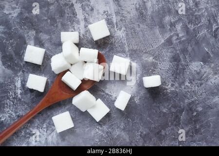 Gros plan du cube de sucre sur la cuillère en bois. Banque D'Images