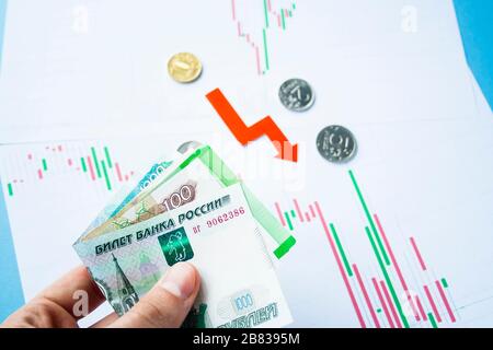 Main masculine tenant des factures roubles sur le taux de change du rouble russe et de la flèche rouge. Dépréciation rouble. Le taux de change du rouble chute. Rouble au dollar Banque D'Images