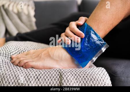 Close-up of Person's Hand Holding Ice Pack Gel Sur la cheville au Home Banque D'Images