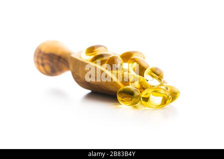 Omega 3 pilules. Capsules de supplément d'huile de poisson dans une pelle en bois isolée sur fond blanc. Banque D'Images