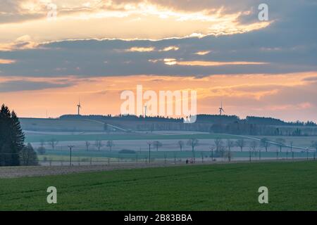 Coucher du soleil avec des nuages au-dessus des collines avec la route et les éoliennes Banque D'Images