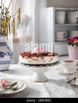 Gâteau sans cuisson à base de crème aigre, biscuits éponge et pêches sur une table blanche Banque D'Images