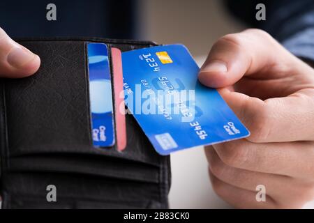 Image rognée d'un homme d'affaires montrant une carte de crédit dans le portefeuille au bureau Banque D'Images