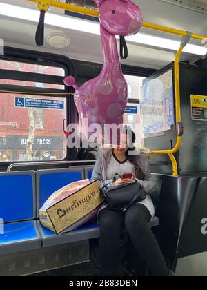 Une femme passe un New York City bus avec un cadeau de jouet pour une mère qui vient d'avoir un garçon. Brooklyn, New York. Banque D'Images