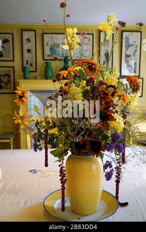 Fleurs dans un vase jaune sur la table à manger de la salle à manger jaune dans la maison de Monet. Région de Normandie. Giverny. France Banque D'Images