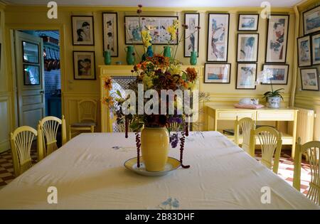 Fleurs dans un vase jaune sur la table à manger de la salle à manger jaune dans la maison de Monet. Région de Normandie. Giverny. France Banque D'Images