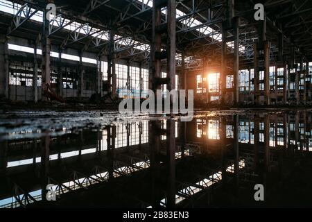 A l'intérieur d'un bâtiment industriel inondé et sale, abandonné, détruit avec réflexion de l'eau Banque D'Images