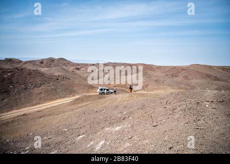 Afrique, Djibouti, Lac Abbe. Sur le chemin menant au lac Abbe, une voiture à quatre roues motrices est stationnée. Trois personnes descendent une colline Banque D'Images