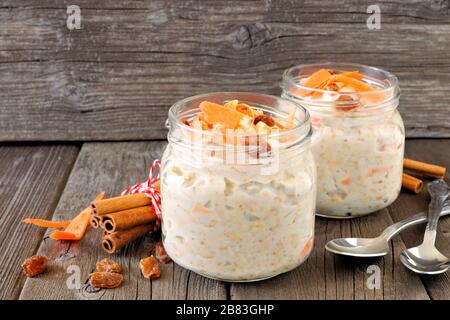 Gâteau aux carottes avoine de nuit avec noix et raisins secs dans des pots de maçon sur un fond rustique en bois Banque D'Images
