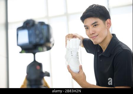 Heureux homme à la maison parlant devant la caméra pour vlog. Jeune homme asiatique travaillant comme blogueur, l'enregistrement vidéo tutorial pour Internet Banque D'Images