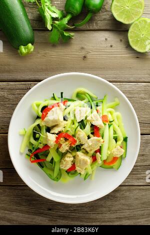 Plat de nouilles aux courgettes en bonne santé avec du poulet sur fond de bois, overhead view Banque D'Images