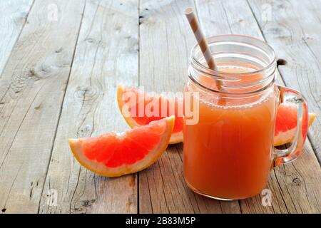 Verre de jus de pamplemousse avec tranches de fruits et pailles sur fond rustique en bois Banque D'Images