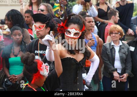 Femme dans un masque de visage décoré dansant avec une jeune fille au carnaval Notting Hill à Londres Banque D'Images