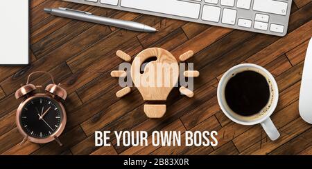 Le symbole et le texte de l'ampoule en bois SONT VOTRE PROPRE BOSS sur un bureau en bois avec bloc-notes, clavier et souris Banque D'Images