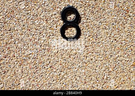 Chiffre 8 / 8 noir sur le mur de pierre à tons chauds. Banque D'Images