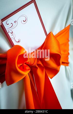 Carte d'invitation à un mariage avec noeud rouge et tissu blanc Banque D'Images