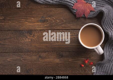 Composition à plat avec écharpe tricotée blanche, tasse de café, sur table de bureau en bois. Style hygge, concept de vacances d'automne ou d'hiver confortable. Plat, dessus vi Banque D'Images