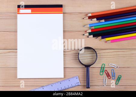 Papeterie scolaire avec feuille vierge de bloc-notes sur table en bois Banque D'Images