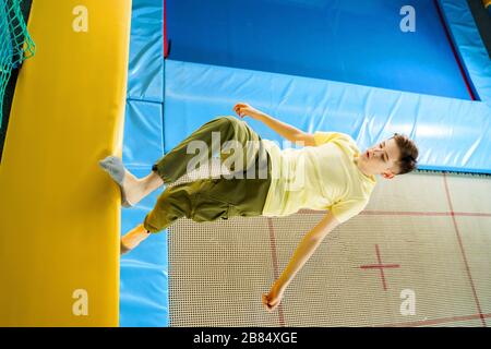 Un adolescent sautant sur le parc du trampoline dans le centre sportif Banque D'Images