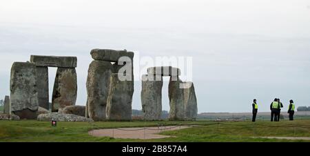 Le personnel de sécurité se tient près de Stonehenge sur la plaine de Salisbury dans le Wiltshire, où les célébrations traditionnelles de l'équinoxe à l'intérieur des pierres ont été annulées après le patrimoine anglais, qui gère l'attraction, a fermé le site jusqu'au 1er mai suivant les conseils du gouvernement sur le coronavirus. Banque D'Images