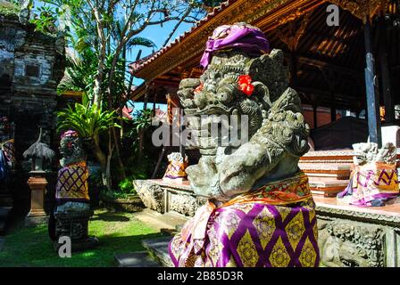 Une statue de gardien devant un temple de Bali vêtu de vêtements traditionnels Banque D'Images