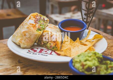 crevettes et burrito de riz sur une plaque blanche avec chips de tortilla et sauce au guacamole et au chili Banque D'Images
