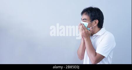 Homme asiatique dans le masque médical maladie pandémique du coronavirus sur fond gris. Le virus COVID-19 de l'épidémie de Chine à la récession mondiale concept pour Banque D'Images