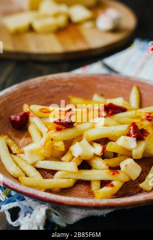 Frites de la poutine sur la surface noire. Plat canadien avec pommes de terre, fromage et sauce Banque D'Images