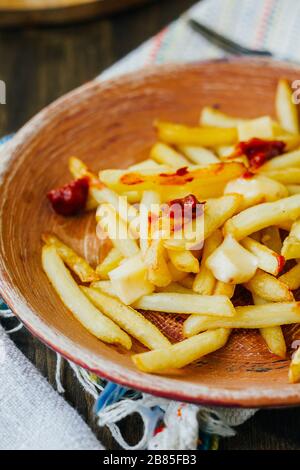 Frites de la poutine sur la surface noire. Plat canadien avec pommes de terre, fromage et sauce Banque D'Images