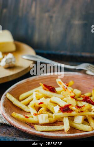 Frites de la poutine sur la surface noire. Plat canadien avec pommes de terre, fromage et sauce Banque D'Images