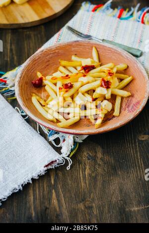 Frites de la poutine sur la surface noire. Plat canadien avec pommes de terre, fromage et sauce Banque D'Images