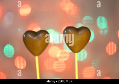 Andy en forme de coeur recouvert de chocolat sur des bâtons. Concept d'amour au chocolat coeur avec des formes sur l'ombre et lumières de flou artistique flou Banque D'Images