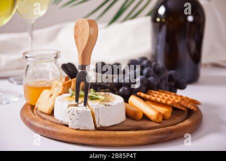 bouteille de vin rouge et assiette avec assortiment de fromages, fruits et autres en-cas pour la fête Banque D'Images