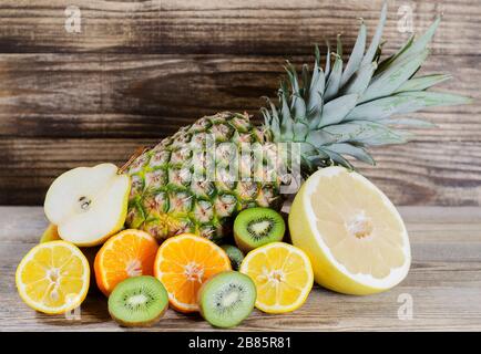 ananas et citron tranché, kiwi, pamela et poire piqués sur fond de bois Banque D'Images