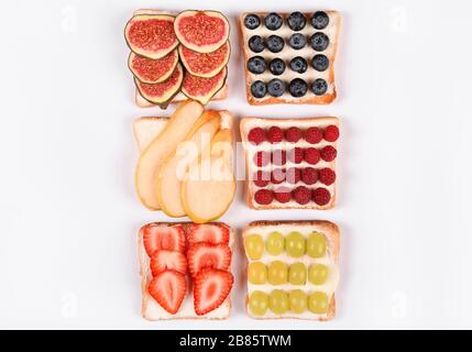 Ensemble avec toasts et différentes garnitures végétaliennes isolées, vue de dessus. Toasts à la poire, aux bleuets, aux framboises, aux raisins, aux fraises, aux figues et aux autres fruits Banque D'Images