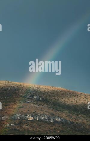 Birght Rainbow surmontant la montagne sur fond gris foncé Banque D'Images