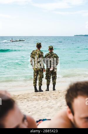 Deux hommes de l'armée en uniforme de camouflage regardent des bateaux et patrouillent sur la plage d'Isla Baru, près de Carthagène, Colombie Banque D'Images