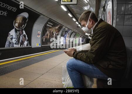 Un homme portant un masque facial dans le métro de Londres, les navetteurs étant parmi les plus exposés à la propagation de l'infection au coronavirus Banque D'Images